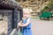 Portrait of cute little blondy toddler girl looking at camera and leaning on a wooden fence in the zoo or city park Child safety c