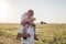 Portrait of cute little boy  and her handsome grandpa looking at camera and smiling on meadow. kid is sitting pickaback