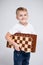 Portrait of cute little boy holding chess board over white