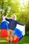 Portrait of cute little boy in public summer park with russian flag on background. Fans child supporting and cheering their