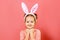 Portrait of a cute little child girl with bunny ears on a colar pink background. Easter concept. Close-up