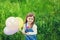 Portrait of cute little girl with beautiful smile holding toy balloons in hand on the flower meadow, happy childhood