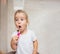 Portrait of cute little girl with blonde hair which cleaning tooth with brush and toothpaste in bathroom. Copyspace