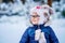 Portrait of a cute little girl in a hat and scarf in winter. preschool child with glasses in the forest. Happy child in