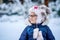 Portrait of a cute little girl in a hat and scarf in winter. preschool child with glasses in the forest. Happy child in