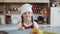 Portrait of a cute little girl in the kitchen dressed as a professional cook looking into the camera and smiling