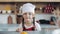 Portrait of a cute little girl in the kitchen dressed as a professional cook looking into the camera and smiling