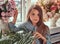 Portrait of a cute little girl with long brown hair and piercing glance wearing a stylish dress, posing with flowers