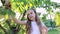 Portrait of a cute little girl at sunset in a green garden. child touches green branch