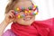 Portrait of cute little girl wearing funny glasses, decorated with colorful smarties, candies