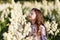A portrait of a cute little girlwith long hair in outside at sunset in the field of white yucca flowers having fun