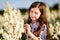A portrait of a cute little girlwith long hair in outside at sunset in the field of white yucca flowers having fun