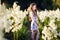 A portrait of a cute little girlwith long hair in outside at sunset in the field of white yucca flowers having fun