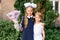 Portrait of a cute little seven year old first-grader girl with a bouquet of flowers with her younger brother ready to go to schoo