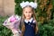 Portrait of a cute little seven year old first-grader girl with a bouquet of flowers ready to go to school. back to school concept