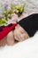 Portrait of cute newborn baby in knitted ladybird costume sleeping on white blanket