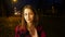 Portrait of a cute pensive smiling teen girl on a night city street.