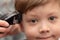 Portrait of a cute preschooler boy whose female hands are cut with a hair clipper. look into the camera. selective focus