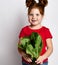 Portrait of a cute red-haired girl holding freshly grown lettuce leaves on a gray background.