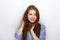 Portrait of cute redhead girl wearing blue striped shirt smiling with happiness and joy while posing against white studio