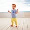 Portrait of cute redhead, one year old baby boy walking on decking