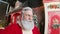 A portrait of cute Santa Claus filming himself in a beautiful New Year\'s decorated studio. POV