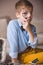 Portrait of cute schoolboy kid in blue shirt sitting on the sofa and looking through a magnifier