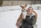 Portrait of cute self-assured basenji dog sitting on the hands of Caucasian senior man