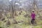 Portrait of cute small confused blond girl in casual pink clothing and dark sunglasses standing alone lost among dry prickly bush