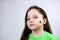Portrait of cute small girl in green T-shirt with green shamrock leaf on her cheek. Saint Patricks Day