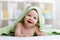 Portrait of cute smiling baby in hooded towel lying on bed after having bathtime