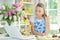 Portrait of cute teen girl using laptop while preparing fresh salad on kitchen table