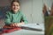 Portrait of cute teen schoolboy sitting at table at making homework