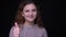 Portrait of cute young brunette wavy-haired student makes finger-up sign to show like and respect on black background.