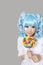 Portrait of cute young woman dressed as a doll holding lollipop over gray background