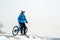 Portrait of Cyclist in Blue Resting with Mountain Bike on Rocky Winter Hill. Extreme Sport and Enduro Biking Concept.