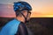 Portrait of a cyclist with helmet, standing looking at dramatic sunset