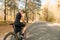 Portrait of a cyclist in a sports outfit standing on the road outside the city and looking into the camera with a serious face.