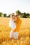 Portrait of a dad holding up in arms his little daughter in a field of wheat