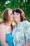 Portrait daughter is kissing her mother on the cheek in the summer sunny day