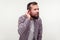 Portrait of deaf bearded man standing with hand near ear and listening carefully to secret conversation. white background