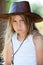 Portrait of deeply offended young girl dressed cowboy leather hat and white shirt, purse lips, injured look