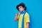 Portrait of defiant boy in yellow t-shirt, scarf and hat doing, on blue background. Copy space