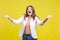 Portrait of delighted beautiful brunette woman raising hands in welcome gesture. indoor studio shot isolated on yellow background