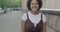 Portrait of delighted young African American lady laughing enjoying joke standing in city street looking at camera