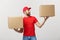 Portrait delivery man in cap with red t-shirt working as courier or dealer holding two empty cardboard boxes. Receiving
