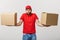 Portrait delivery man in cap with red t-shirt working as courier or dealer holding two empty cardboard boxes. Receiving