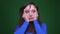 Portrait of depressed brunette businesswoman suffering from migraine on green background.