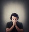 Portrait of depressed young man keeps hands together as prayer, eyes closed, head down isolated on grey background. Desperate guy