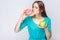 Portrait of desiring young beautiful girl in blue blouse standing, holding pink donut and green apple in the hands and wanted